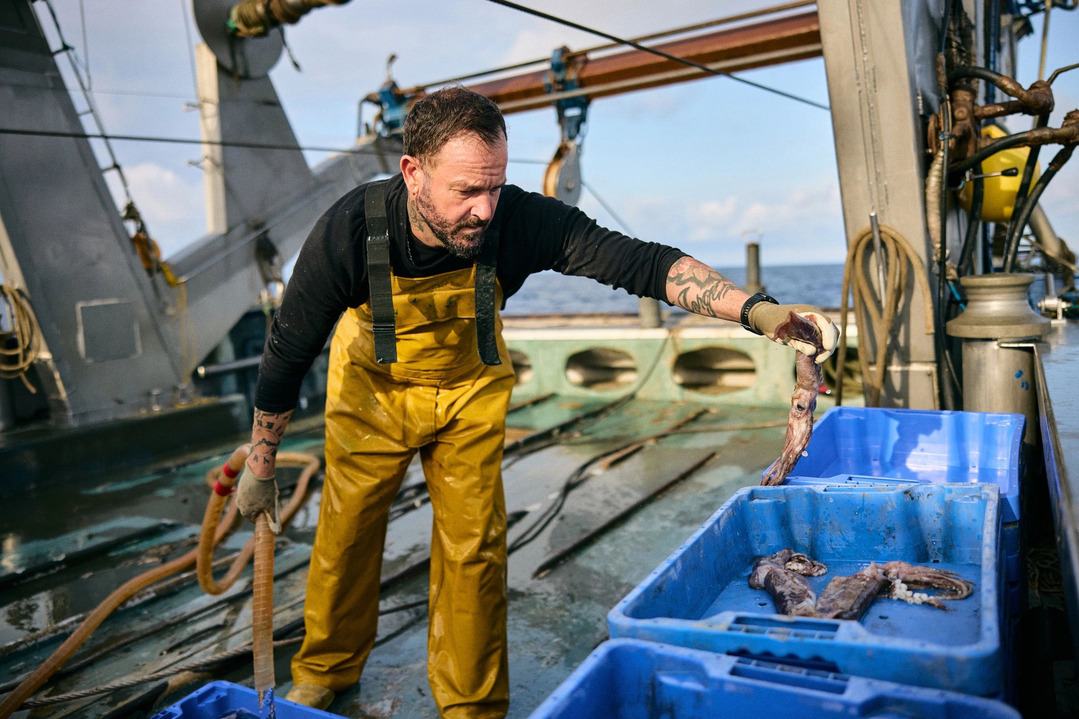 Fisherman in bib overalls holding squid